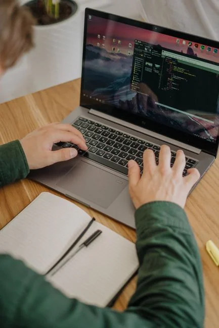 A woman enjoys coffee while browsing the web on a laptop at a home office desk.